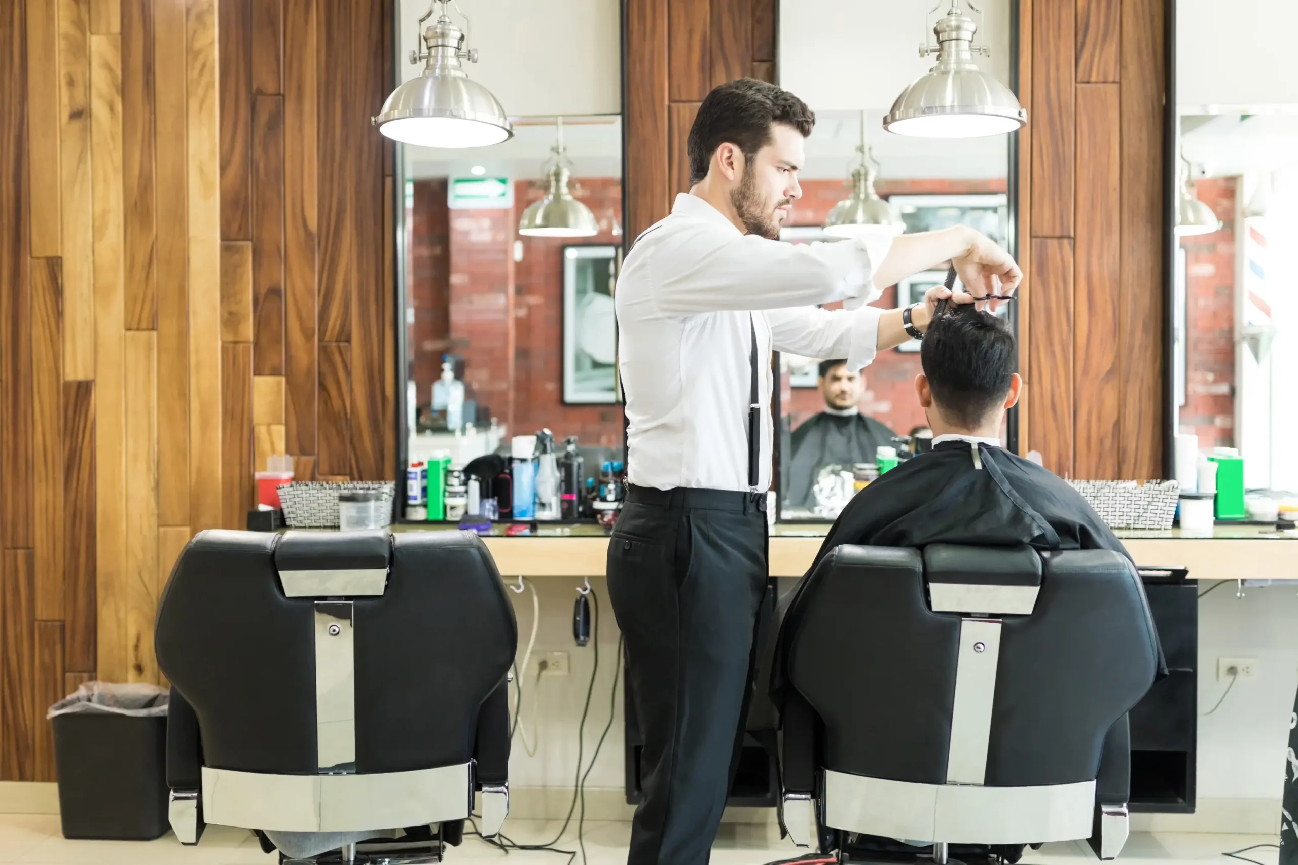 Barber giving a customer a haircut inside a modern barbershop.