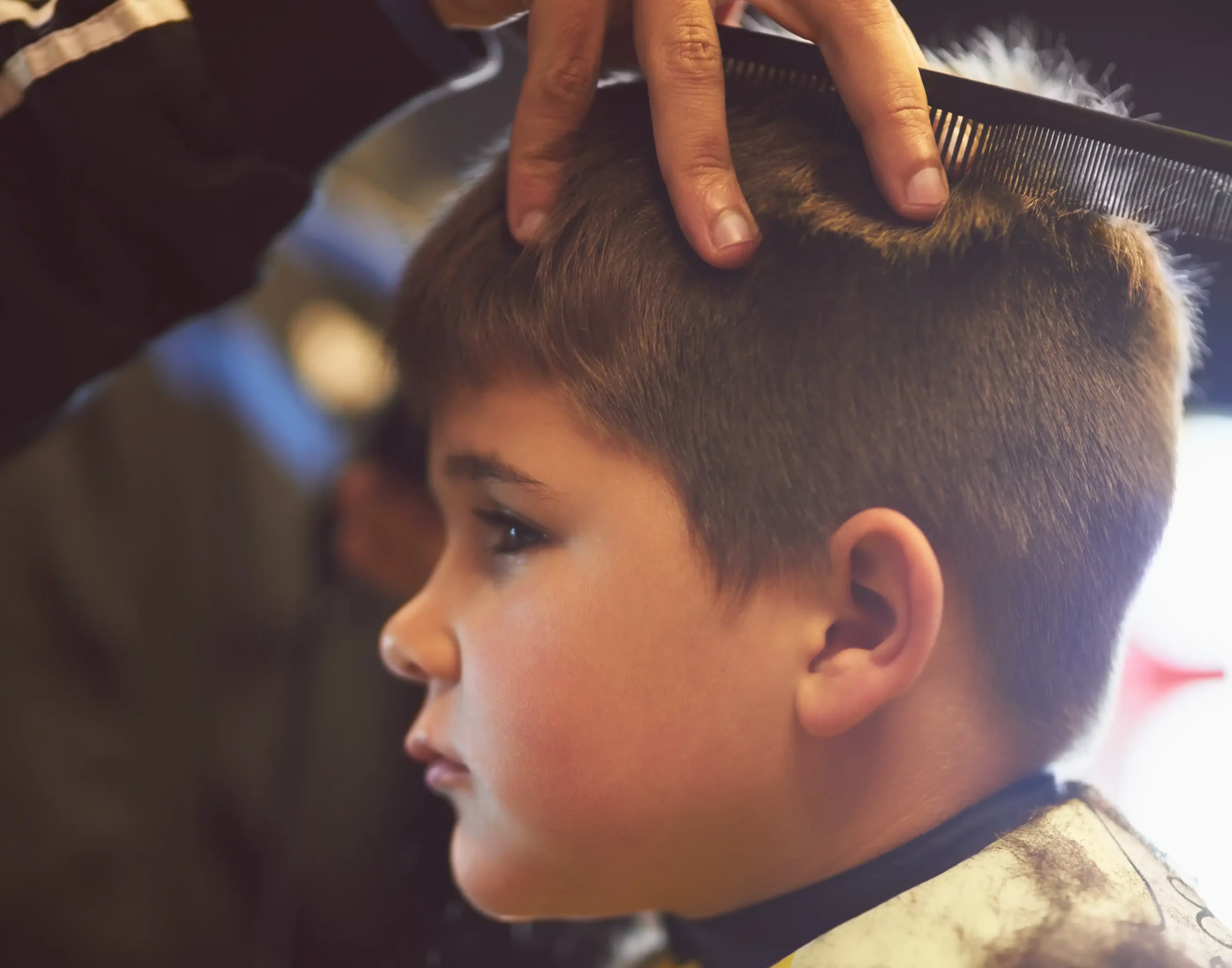 : A boy getting a trim during kids' haircut services at a barbershop.