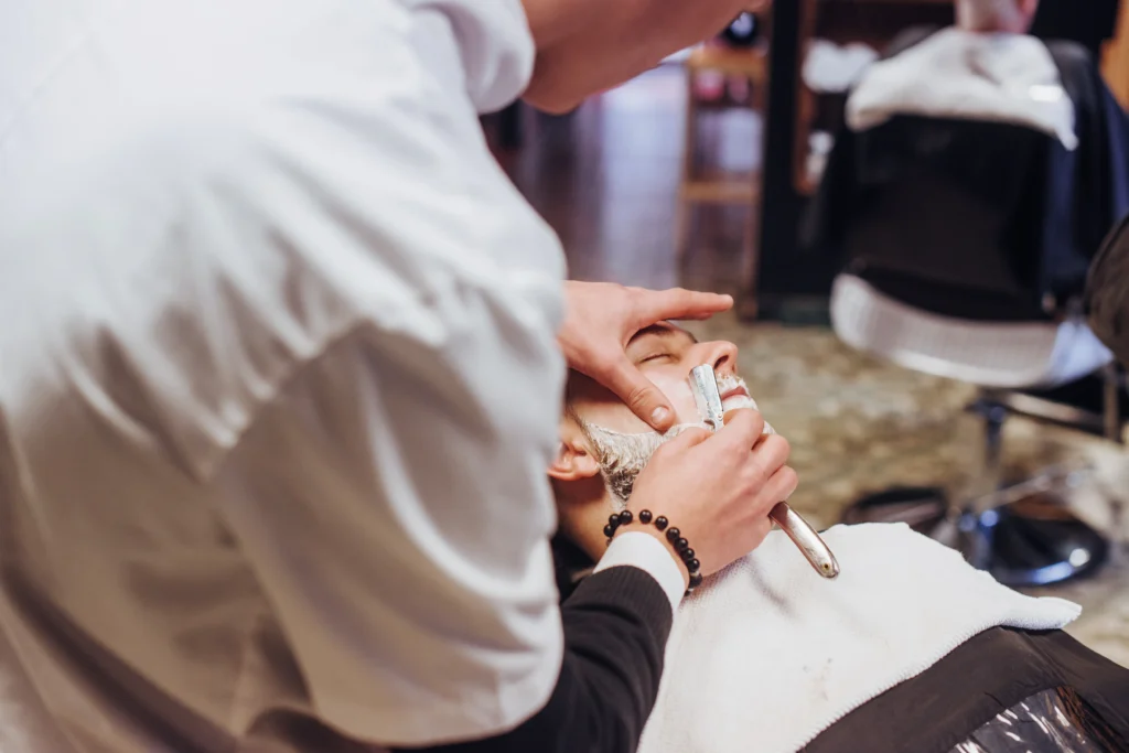A barber expertly gliding a razor for a precise shave, highlighting the smooth finish of professional shaves.
