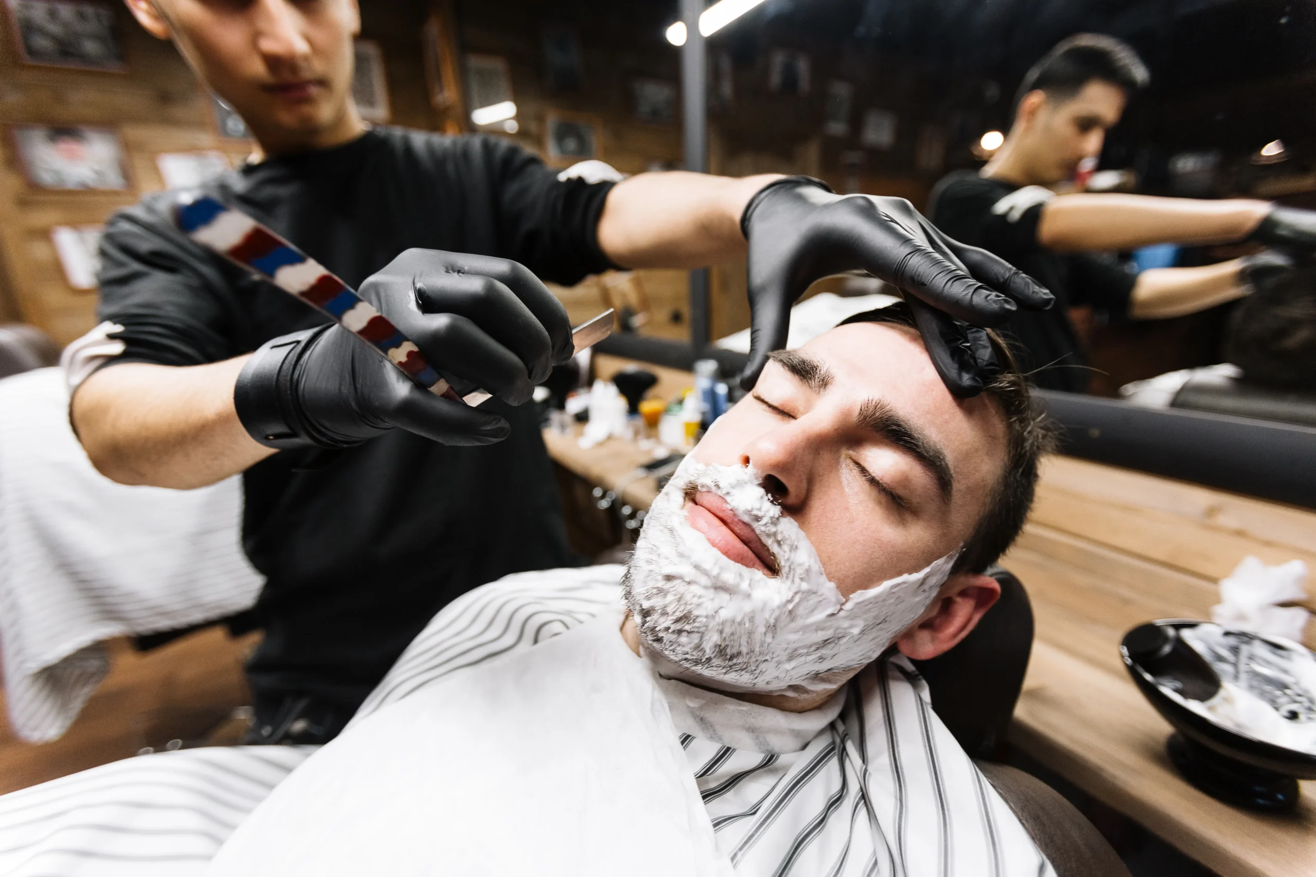 A barber providing a shave to a client, showcasing the precision and care that make professional shaves superior to DIY.